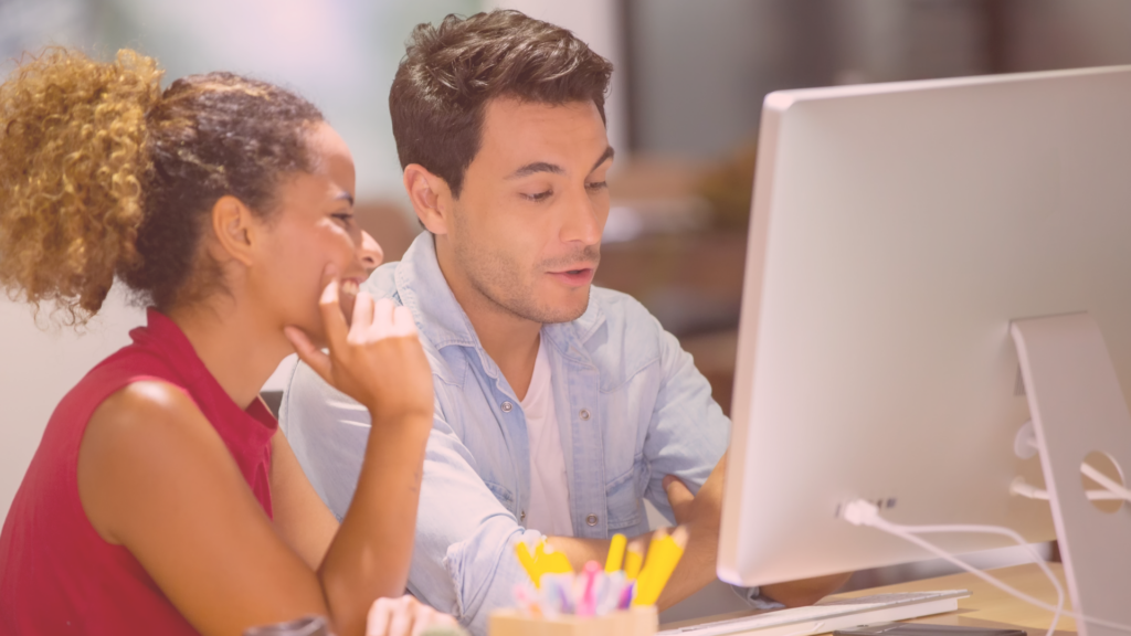 Two colleagues collaborating at a computer in a creative workspace